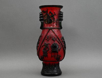 un vase rouge orné de motifs noirs, posé sur une table