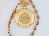 a gold pocket watch on a chain with a chain around it