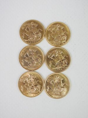 six pièces d'or sont disposées en ligne sur une surface blanche