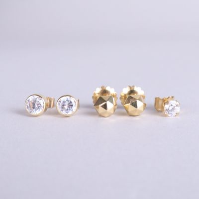 un lot de trois boucles d'oreilles clous en or serties de diamants sur fond blanc