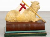a statue of a sheep with a flag on top of a pile of books