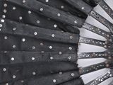a black fan with silver dots on it on a white surface