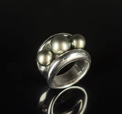 a close up of a silver ring with pearls on a black surface