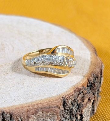 a gold ring with two diamonds on it on a wood slice