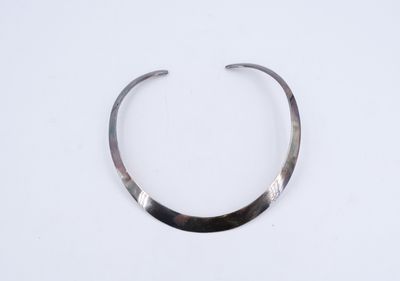 gros plan d'un collier en argent sur une surface blanche