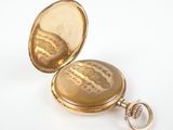 a gold pocket watch with a chain on a white surface