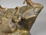 bronze statue of a bird on a rock with a gray background