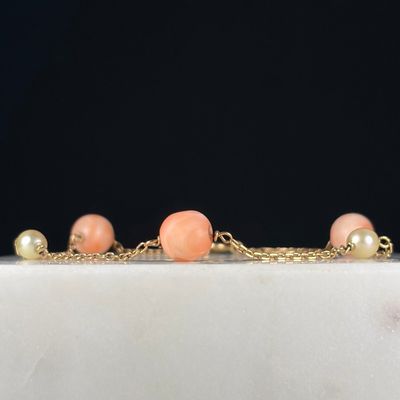 a close up of a gold chain bracelet with peach beads