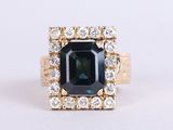 an image of a ring with an emerald stone surrounded by diamonds