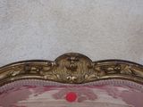 a pink couch with a gold frame and a red dot on it