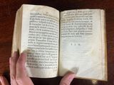 a person holding an open book on a table
