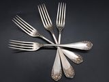 four forks are arranged in a circle on a black surface