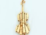 a gold violin brooch on a white surface