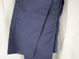 un pantalon bleu marine suspendu à un cintre en bois sur un drap blanc