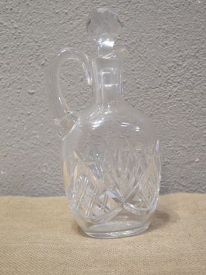 une carafe en verre transparent munie d'une anse, posée sur une table