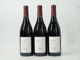 trois bouteilles de vin rouge sont posées sur une surface blanche