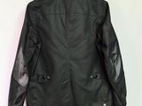 the back of a black leather jacket hanging on a white wall