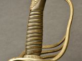 a close up of a sword with a gold handle on a gray background