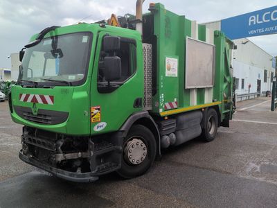 a green garbage truck that is parked in a parking lot