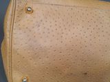 tan ostrich leather handbag on grey background with silver hardware