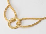 a close up of a gold necklace on a white surface