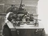 an old photo of a military vehicle driving down the street
