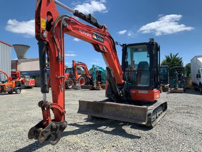 une photo montrant une pelleteuse rouge garée sur un parking