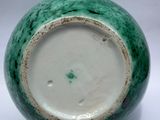 a green and white vase sitting on a white surface