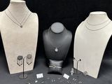 three mannequins with necklaces and earrings on display on a black background