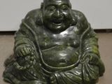 une statue représentant un Bouddha souriant assis par terre
