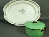 a green pot with a lid next to a plate with a picture of a tree on it