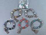 six bracelets différents, ornés de pompons et de perles, posés sur une table