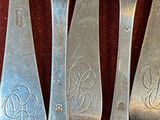 three silver spoons and a fork with a monogram on them