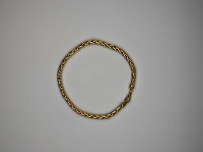 gros plan d'un bracelet en or sur une surface blanche