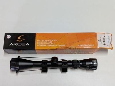 a close up of a rifle scope with a box on a table