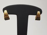 une paire de boucles d'oreilles dorées posées sur un support noir