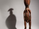 a wooden statue of a man with a bird on his head