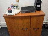 a wooden cabinet with a laptop on top of it next to a coffee maker