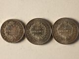 three coins are shown on a white surface, one of which has a crown and the other of which is