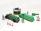 a green toy truck and some construction figures on a white surface