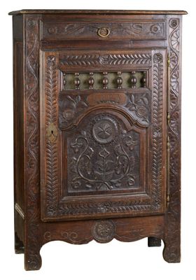 une vieille armoire en bois dont la façade est ornée de sculptures élaborées