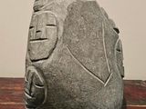 a stone sculpture on a wooden table with a wall in the background