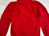 a red hoodie sitting on top of a table next to a pair of shoes