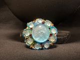 an image of a ring with blue and green stones on a black surface