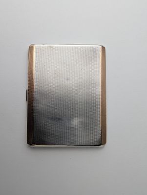 a silver cigarette case sitting on a white surface