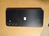 the back of a black cell phone sitting on top of a wooden table