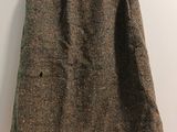 brown tweed skirt hanging on a hanger against a white wall