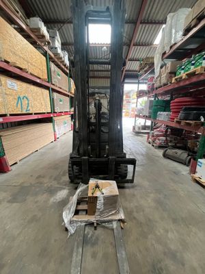 a forklift in a warehouse with a lot of boxes on the floor
