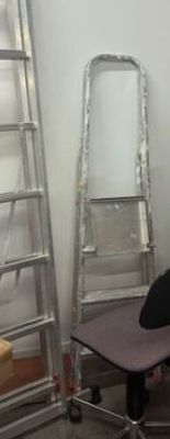 two ladders leaning against the wall next to a desk