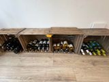 de nombreuses bouteilles de vin dans des caisses en bois posées par terre